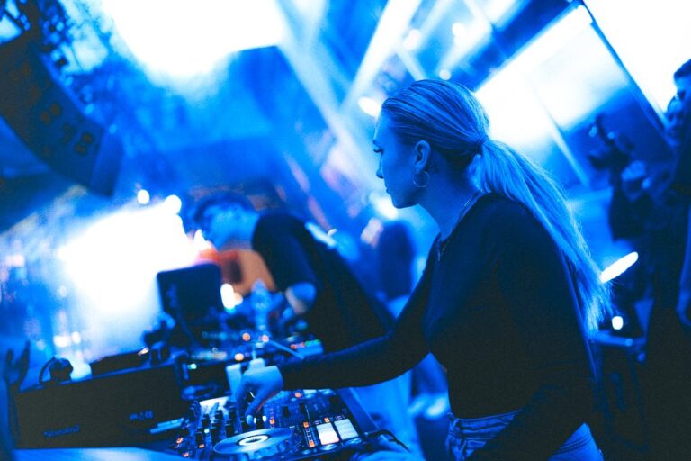 DJane Polly mixt bei einem Abendevent in blauem Licht